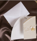 <p>Приглашение на свадьбу, изготовленное из белого глянцевого картона и сгибается на три части. С внешней стороны открытка бежевого цвета, с изображением кружева, двух обручальных колец в белом сердечке, а внутри по центру печатается текст. В стоимость включен белый конверт .</p>